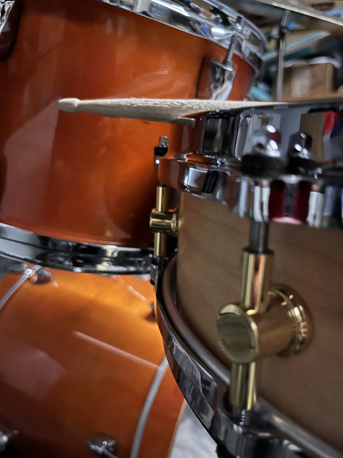 A close-up view of a drum set featuring a snare drum and tom, with a drumstick resting on top.